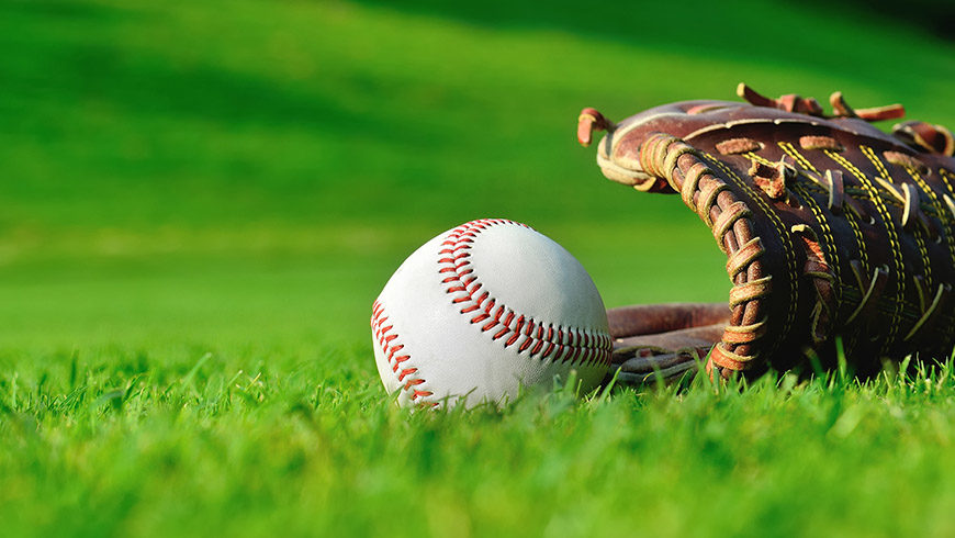 baseball sitting next to glove on grass